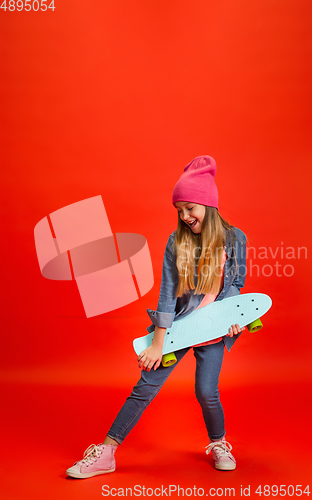 Image of Caucasian little girl portrait isolated on red studio background. Cute stylish model