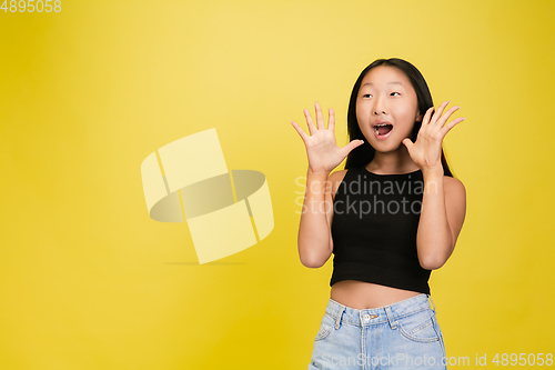 Image of Portrait of young asian girl isolated on yellow studio background