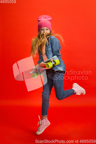 Image of Caucasian little girl portrait isolated on red studio background. Cute stylish model