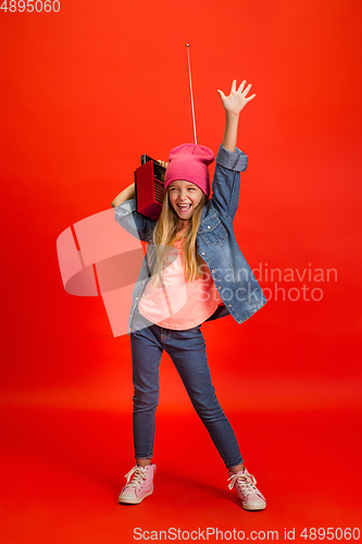 Image of Caucasian little girl portrait isolated on red studio background. Cute stylish model