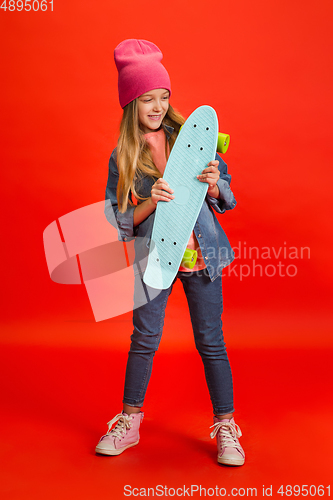 Image of Caucasian little girl portrait isolated on red studio background. Cute stylish model