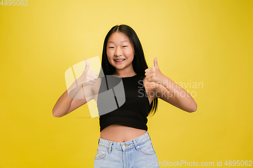 Image of Portrait of young asian girl isolated on yellow studio background