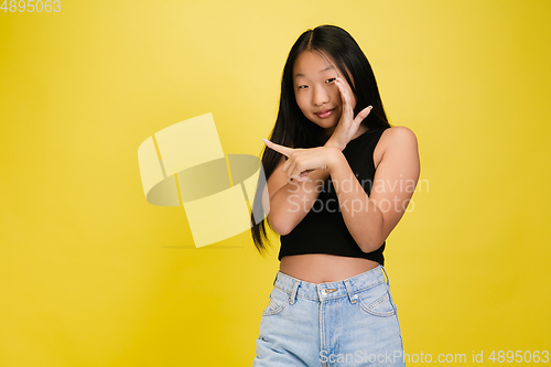 Image of Portrait of young asian girl isolated on yellow studio background