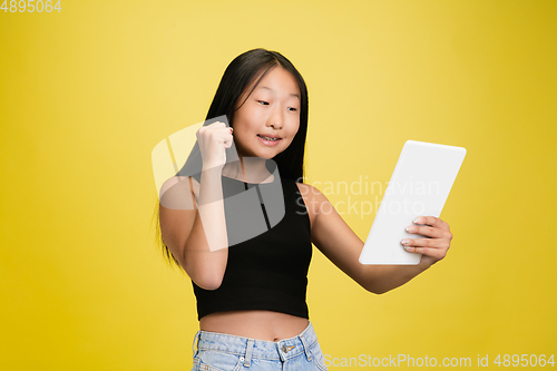 Image of Portrait of young asian girl isolated on yellow studio background