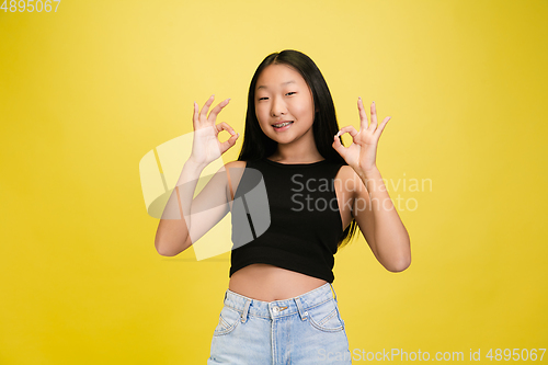 Image of Portrait of young asian girl isolated on yellow studio background