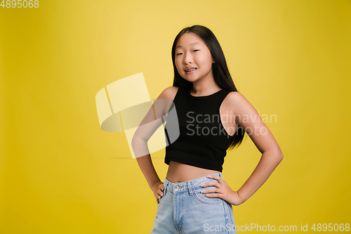 Image of Portrait of young asian girl isolated on yellow studio background