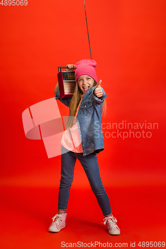 Image of Caucasian little girl portrait isolated on red studio background. Cute stylish model