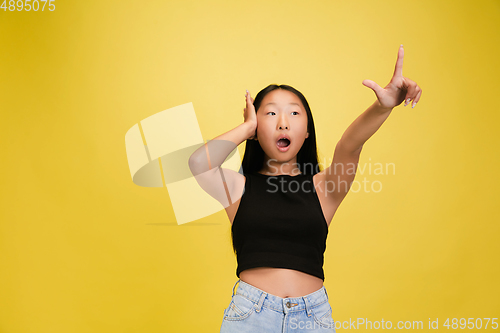 Image of Portrait of young asian girl isolated on yellow studio background