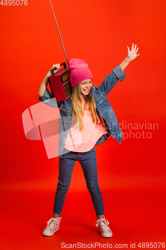 Image of Caucasian little girl portrait isolated on red studio background. Cute stylish model