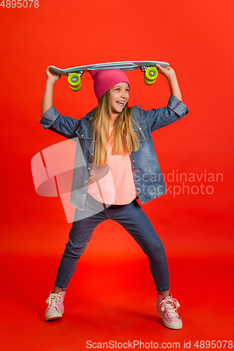 Image of Caucasian little girl portrait isolated on red studio background. Cute stylish model