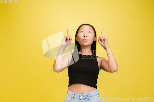 Image of Portrait of young asian girl isolated on yellow studio background