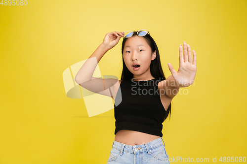 Image of Portrait of young asian girl isolated on yellow studio background