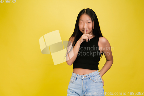 Image of Portrait of young asian girl isolated on yellow studio background