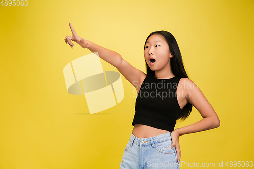 Image of Portrait of young asian girl isolated on yellow studio background