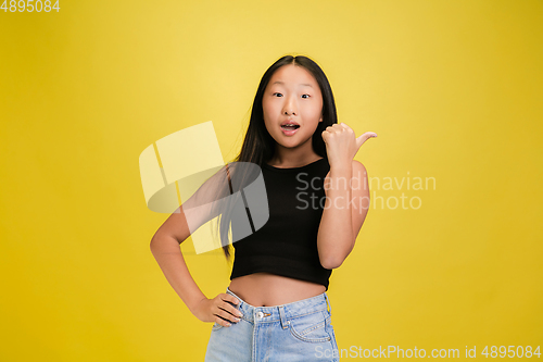 Image of Portrait of young asian girl isolated on yellow studio background