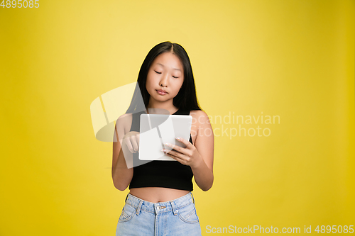 Image of Portrait of young asian girl isolated on yellow studio background