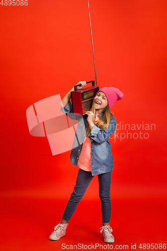 Image of Caucasian little girl portrait isolated on red studio background. Cute stylish model