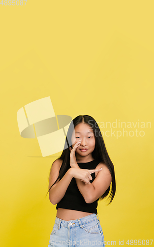 Image of Portrait of young asian girl isolated on yellow studio background
