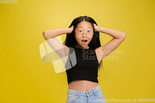 Image of Portrait of young asian girl isolated on yellow studio background