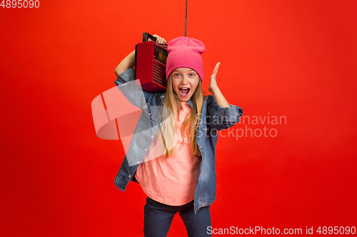 Image of Caucasian little girl portrait isolated on red studio background. Cute stylish model