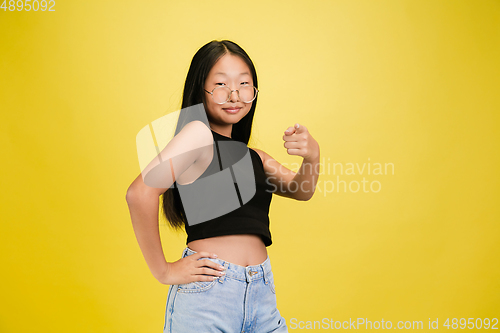 Image of Portrait of young asian girl isolated on yellow studio background