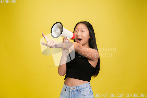 Image of Portrait of young asian girl isolated on yellow studio background