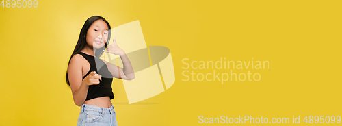 Image of Portrait of young asian girl isolated on yellow studio background