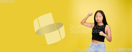 Image of Portrait of young asian girl isolated on yellow studio background