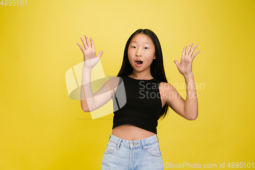 Image of Portrait of young asian girl isolated on yellow studio background