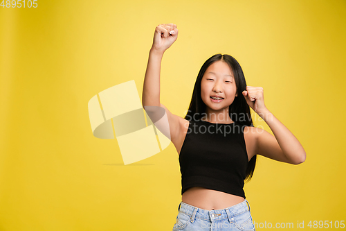 Image of Portrait of young asian girl isolated on yellow studio background