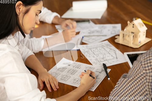 Image of Male architect-engineer presents project of future house for young family.