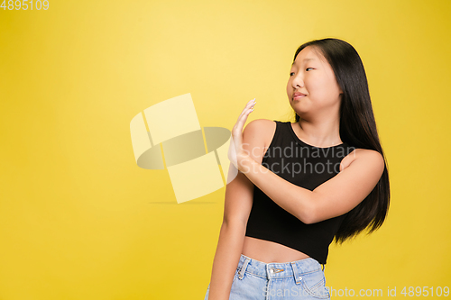 Image of Portrait of young asian girl isolated on yellow studio background