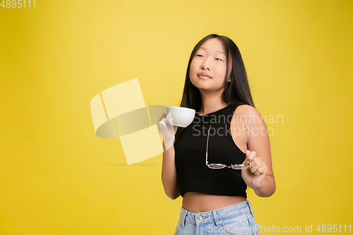 Image of Portrait of young asian girl isolated on yellow studio background