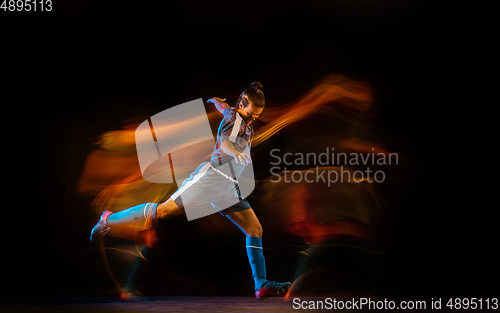Image of Football or soccer player on black background in mixed light, fire shadows