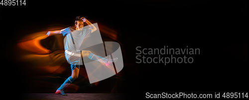 Image of Football or soccer player on black background in mixed light, fire shadows