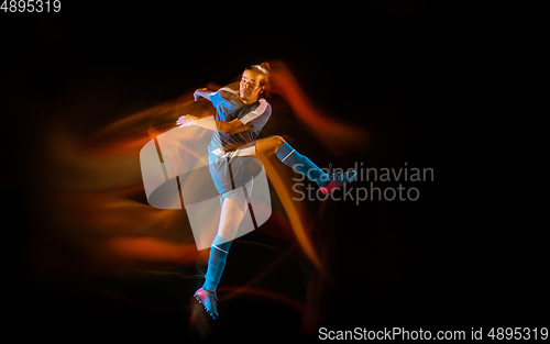 Image of Football or soccer player on black background in mixed light, fire shadows