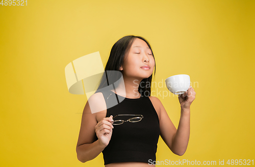 Image of Portrait of young asian girl isolated on yellow studio background