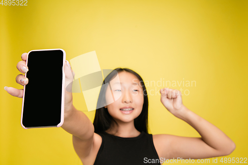 Image of Portrait of young asian girl isolated on yellow studio background