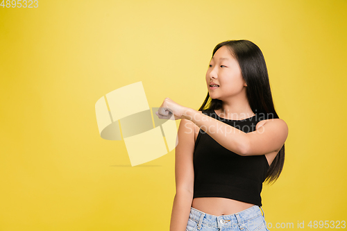 Image of Portrait of young asian girl isolated on yellow studio background