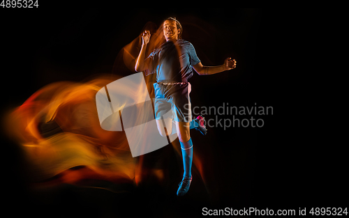 Image of Football or soccer player on black background in mixed light, fire shadows