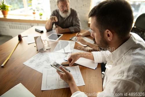 Image of Male architect-engineer presents project of future house for young family.