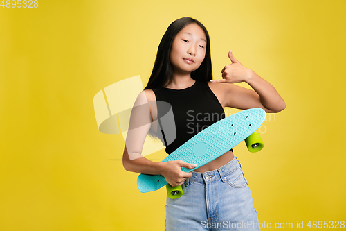 Image of Portrait of young asian girl isolated on yellow studio background