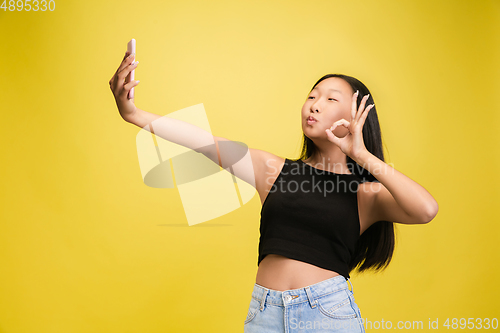 Image of Portrait of young asian girl isolated on yellow studio background