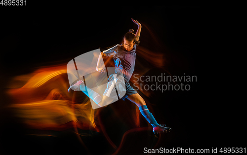 Image of Football or soccer player on black background in mixed light, fire shadows
