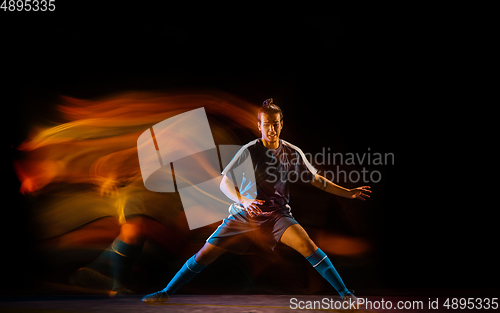 Image of Football or soccer player on black background in mixed light, fire shadows