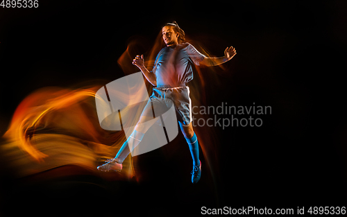 Image of Football or soccer player on black background in mixed light, fire shadows