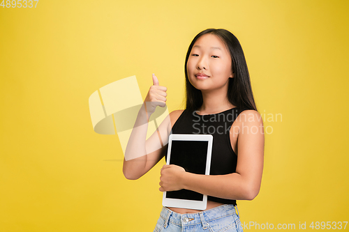 Image of Portrait of young asian girl isolated on yellow studio background