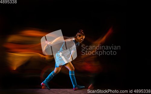 Image of Football or soccer player on black background in mixed light, fire shadows