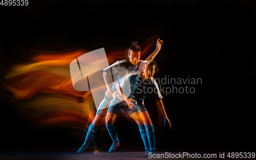 Image of Football or soccer player on black background in mixed light, fire shadows