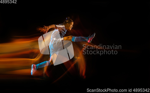 Image of Football or soccer player on black background in mixed light, fire shadows